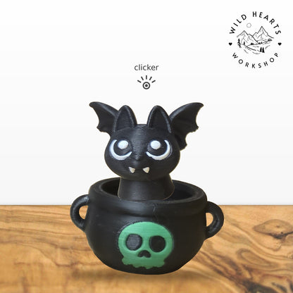 Bat clicker top (black bat) seated in the black cauldron with green skull base