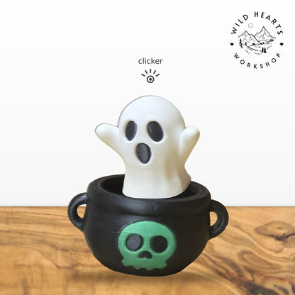 Ghost clicker top (white ghost) seated in the black cauldron with green skull base