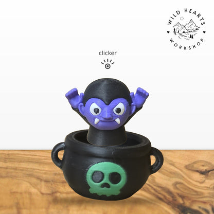 Vampire clicker top (purple vampire) seated in the black cauldron with green skull base