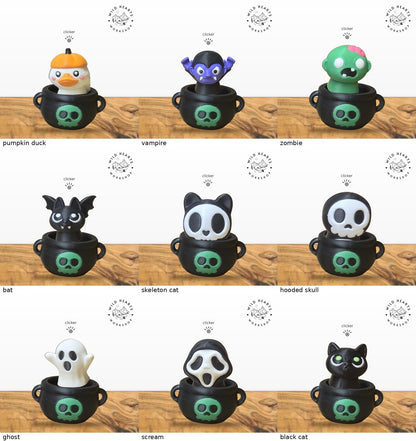 All 9 Halloween clicker tops shown in the black cauldron with green skull