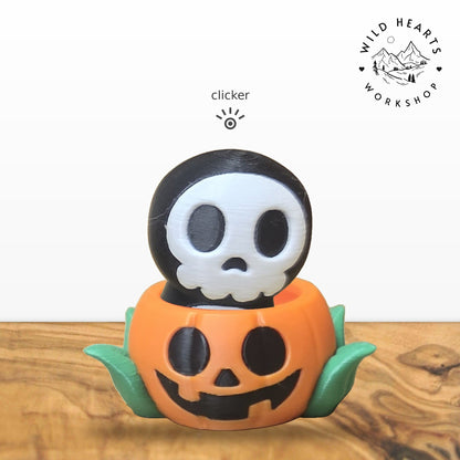 Hooded Skull clicker top (hooded skeleton skull) seated in the orange jack-o-lantern pot with green leaves base